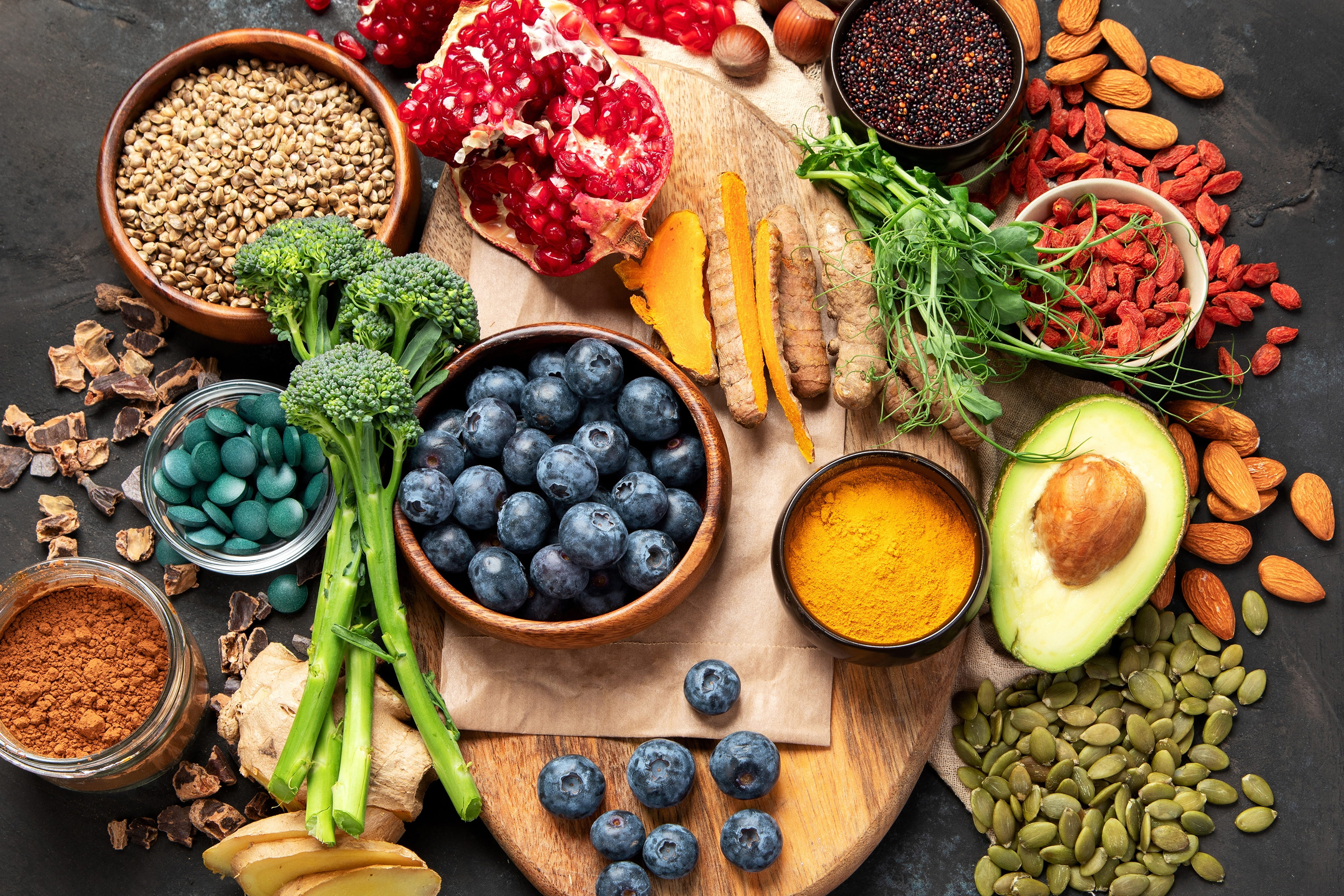 Colourful flat-lay of nutrient-dense superfoods including blueberries, pomegranate, turmeric, avocado, broccoli and seeds, representing the anti-inflammatory, hormone-supporting diet recommended during perimenopause